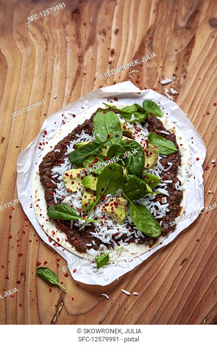 A tortilla with black bean mousse, rice, avocado and spinach