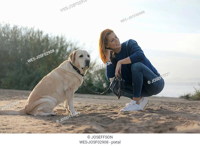 Germany, Hamburg, woman with dog on beach at the Elbe shore