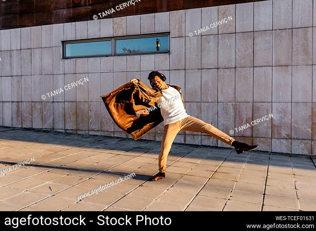 Male dancer enjoying dance while practicing against building
