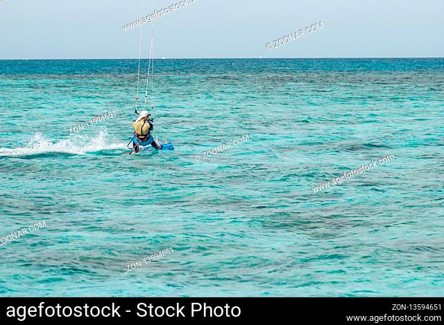 professional kiter glide the water surface of the ocean at great speed. Back view behind wide shot