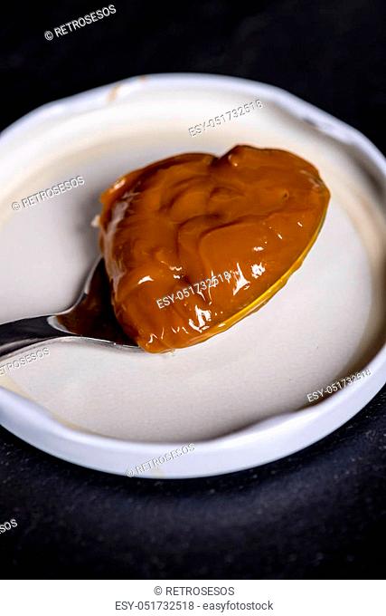 Dulce de leche in a spoon, very sweet creme caramel or praline creme from Argentina, made of milk boiled with sugar for hours