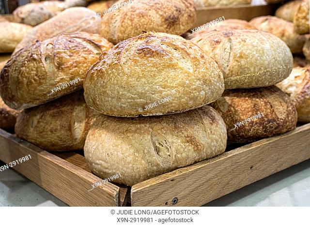 New York City, Manhattan. Frshly Baked Loaves of Sourdough Bread, Artfully Arranged on a Wooden Tray. Displayed and Offered for Sale in a Gourmet NYC Food...
