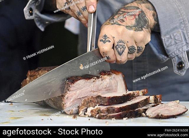 Themed photo grilling. Grilled pork, roast pork is portioned with a meat knife, cut into slices. Grilling on charcoal grill, grilled meat, charcoal