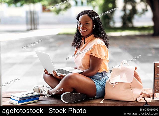 african student girl in earphones with laptop