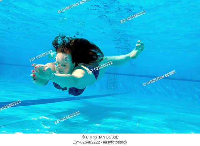 a woman swimming underwater in pool