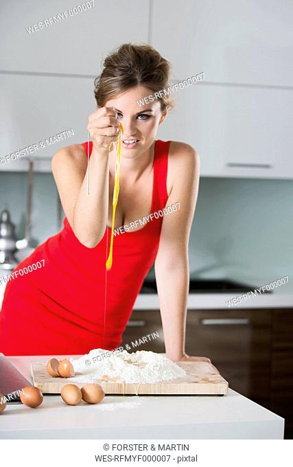 Germany, Young woman squeezing eggs in flour