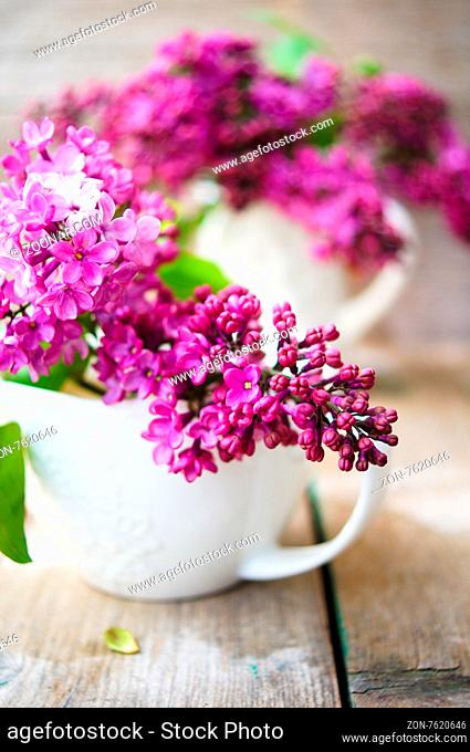 Lilac flowers in a pot and cup of tea in rustic interior