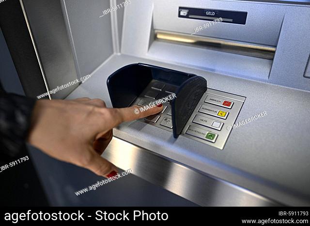 Woman typing in secret code at the cash machine of a savings bank, Waiblingen, Baden-Württemberg, Germany, Europe