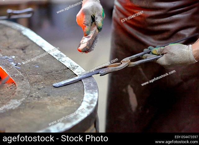 Forging an iron handmade product in a craft forge workshop