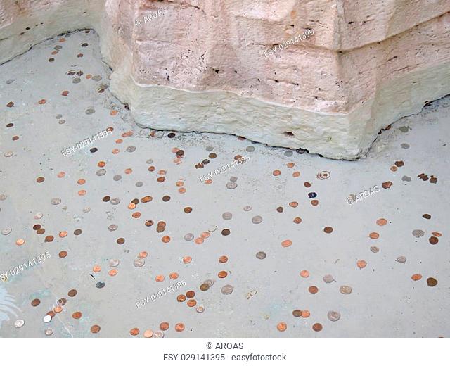Many different coins under water in a fountain