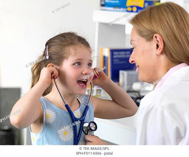 Doctor comforting a 5 year old Girl by playing with her stethoscope in a clinic