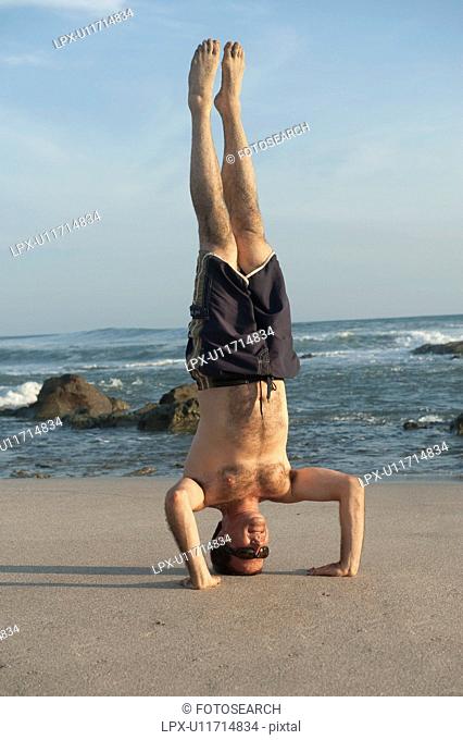 Man in Yoga headstand position along Mal Pais coastline in San Jose Costa Rica