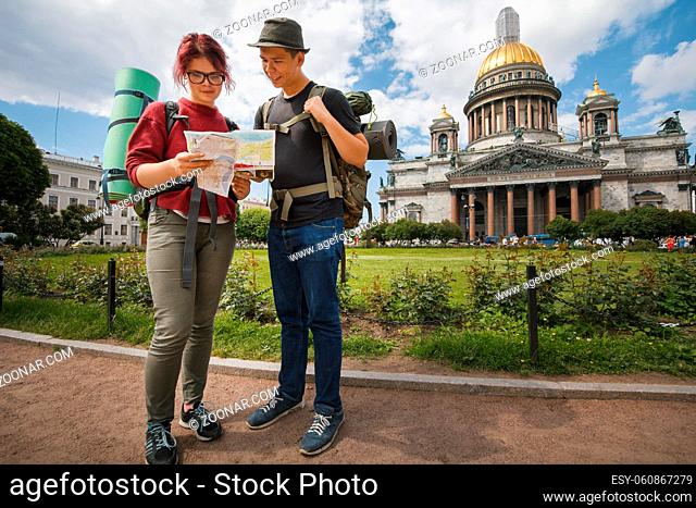 Young tourists check the route on the paper map near Kazan Kathedral of Saint Petersburg, Russia - portrait