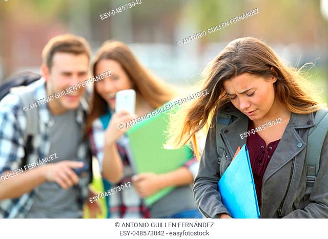 Bullying victim being video recorded on a smartphone by classmates in the street with a unfocused background