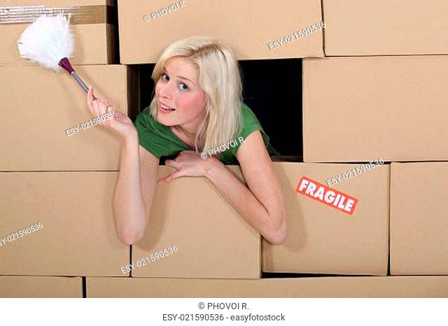 Woman with a feather duster surrounded by packing boxes