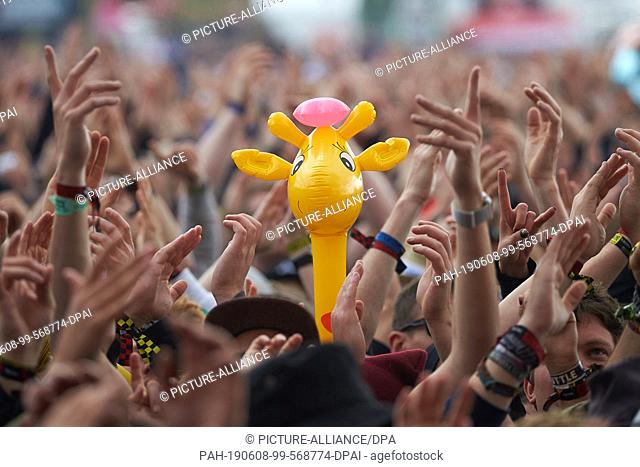 08 June 2019, Rhineland-Palatinate, Nürburg: Fans celebrate the performance of the band ""Feine Sahne Fischfilet"" with an inflatable giraffe in front of the...
