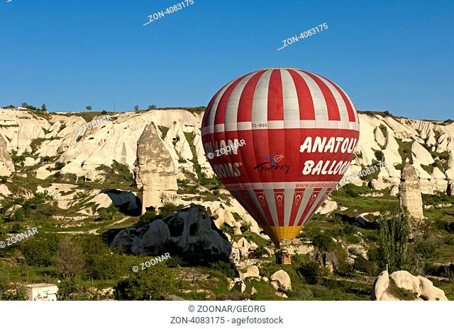 Heissluftballon von Anatolian Balloons schwebt über den Tuffsteinfelsen von Kappadokien, Göreme, Türkei / Hot air balloon of Anatolian Balloons hovering over...