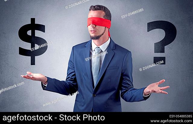 Serious businessmen standing in front of a grey wall with red ribbon on his eye, holding dollars