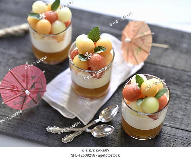 Vegan melon desserts in glasses with melon jelly, whipped sour cream and a trio of different coloured melon balls