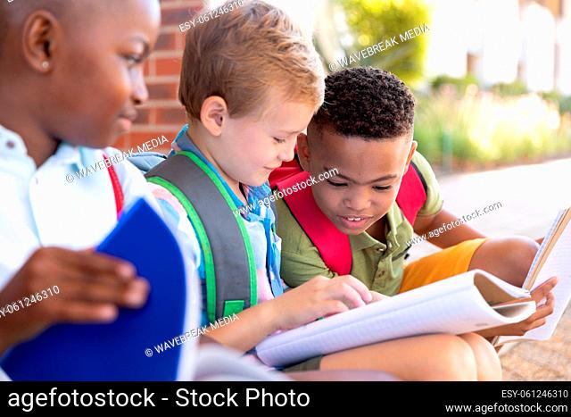 African american elementary schoolboy looking male classmates studying at school entrance