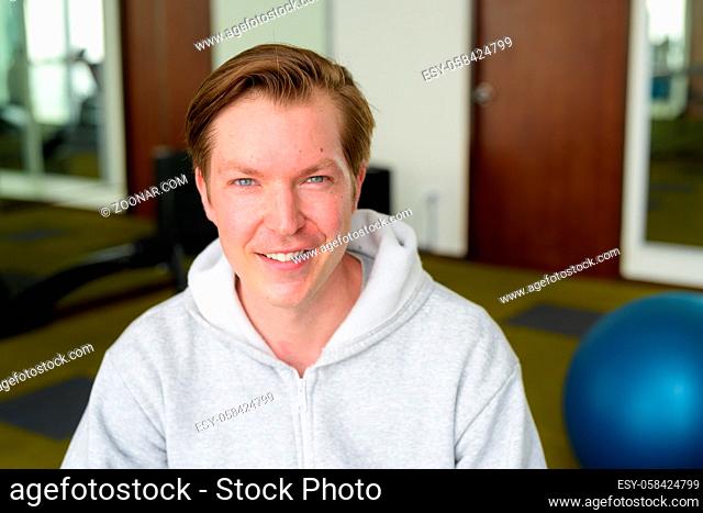 Portrait of young handsome Scandinavian man with hoodie ready for exercising at the gym