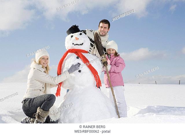 Germany, Bavaria, Munich, Family making a snowman, portrait