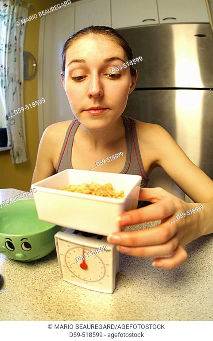 Young woman weighing food on a diet scale