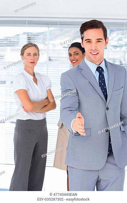 Businessman giving his hand and standing in front of his colleagues