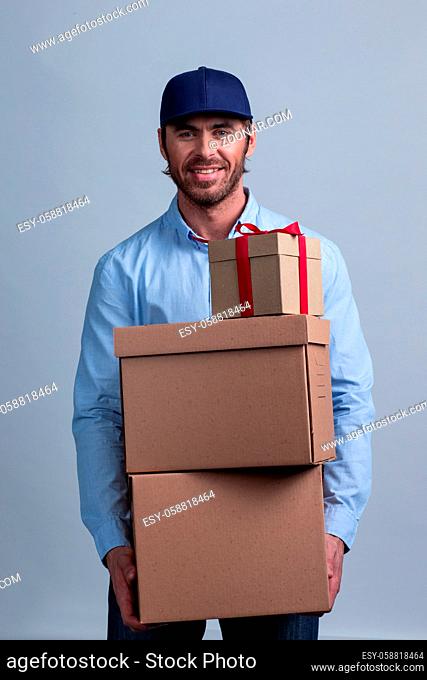 Happy smiling delivery man in uniform cap holding box stack
