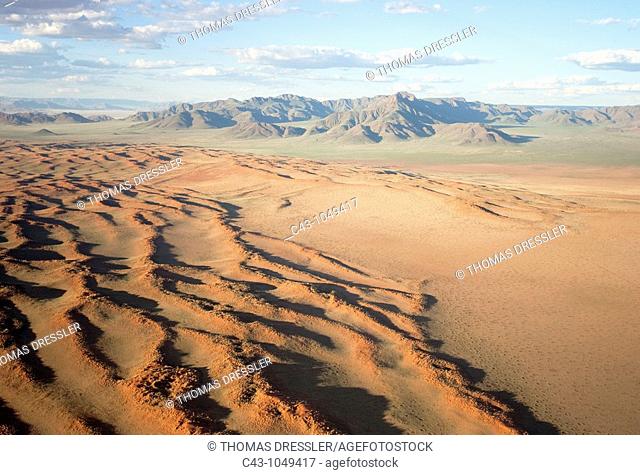 Namibia - Aerial view of grass-grown sand dunes and isolated mountain ridges at the edge of the Namib Desert  In March during the rainy season with a delicate...