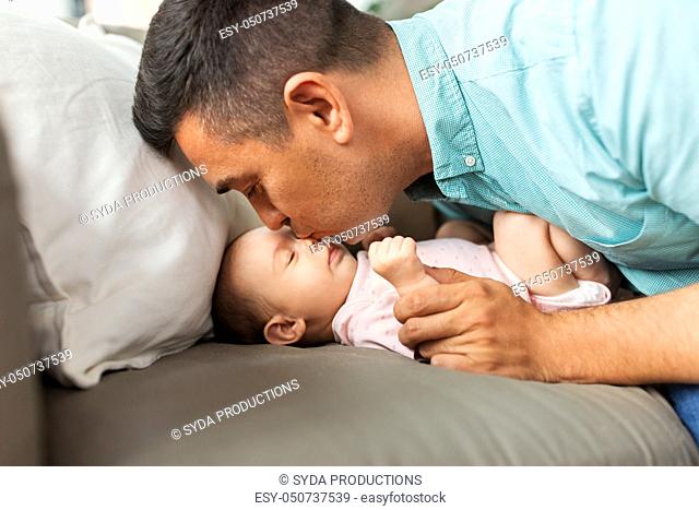middle aged father kissing baby daughter at home