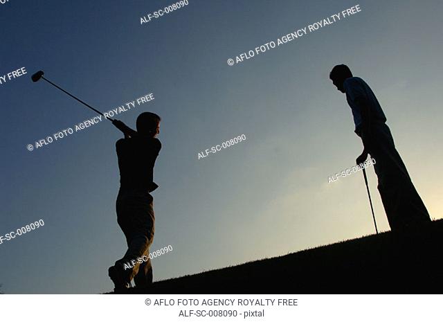 Silhouette of a man in action hitting a golf shot