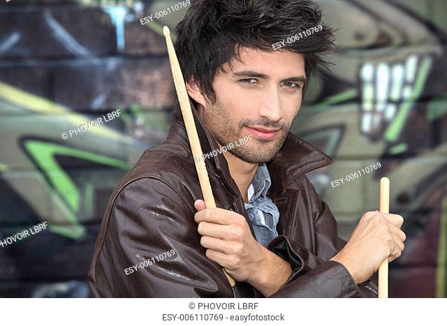 Drummer standing in front of graffiti
