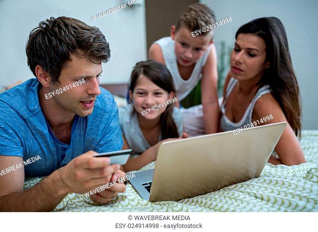 Family doing online shopping on laptop in bedroom