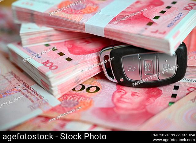 ILLUSTRATION - 12 December 2023, China, Peking: ILLUSTRATION - A car key lies on a table under several Chinese renminbi (yuan) bills