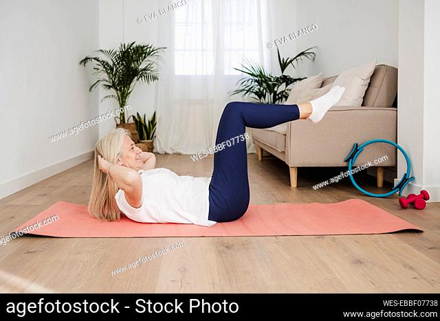 Mature woman doing sit-ups on mat at home