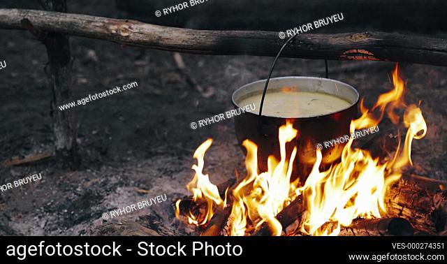 Old Retro Camp Saucepan Boiled Water For Soup Preparation On A Fire In Forest. Flame Fire Bonfire At Summer Evening