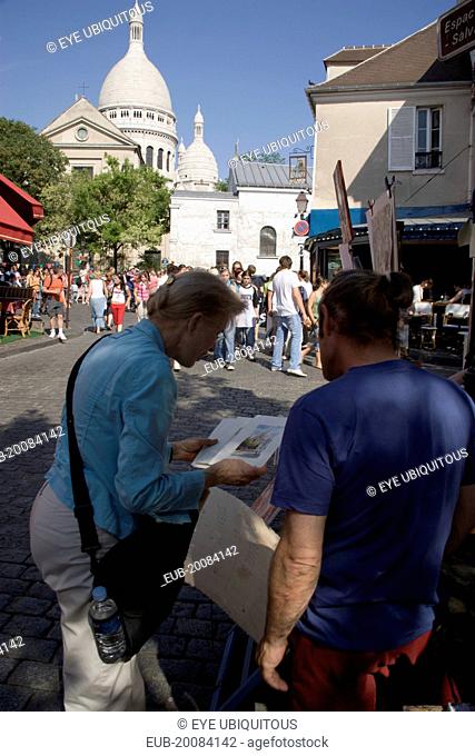 Montmartre Place du Tertre a square beside the church of Sacre Couer with a tourist discussing a painting with an artist vendor