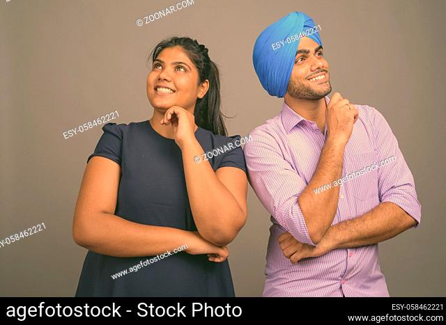 Studio shot of young Indian couple together and in love against gray background