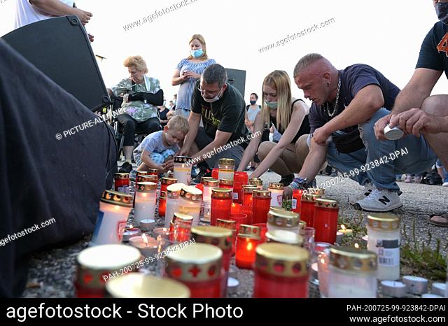 25 July 2020, Saxony-Anhalt, Querfurt: Participants of the commemoration ceremony light candles. Around 400 people held a vigil on Saturday evening in Querfurt...