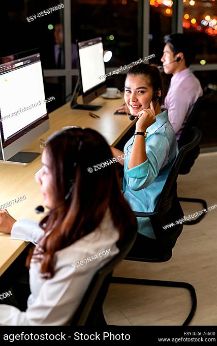 Asian young adult confidence operator colleague team with headsets working in a call center at night as customer service and technical support