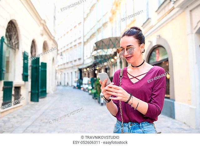 Happy woman with smartphone in european street. Young attractive tourist outdoors in Vienna city