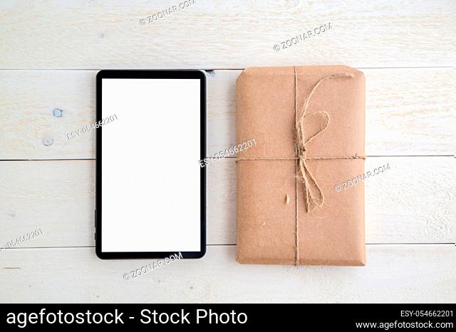 parcel, gift Packed in eco-friendly paper and tablet on light wooden background. the view from the top