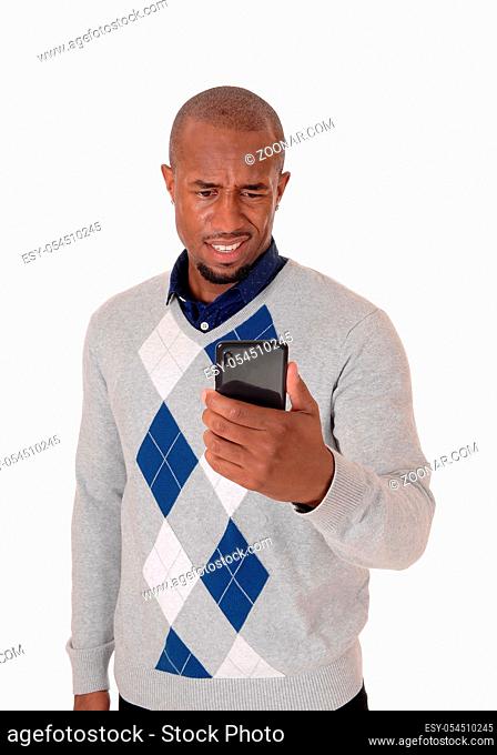 A young angry African American man standing in a sweater with his phone in his hand confused what he sees, isolated for white background