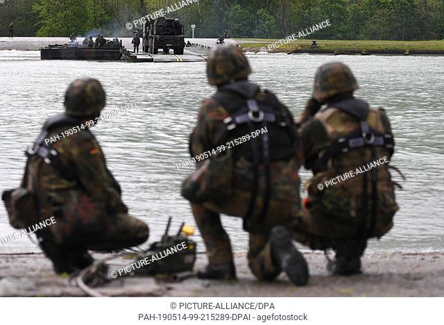 14 May 2019, Bavaria, Flintsbach: Combat vehicles are set over the Inn River with a folding floating bridge used as a ferry