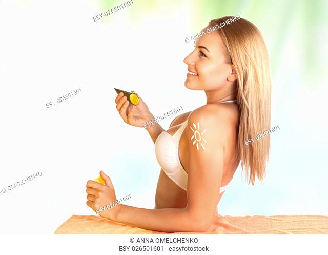 Beautiful young girl using sunscreen on the beach to protect her skin from sunburn, healthy sunbathing, woman enjoying happy summer vacation