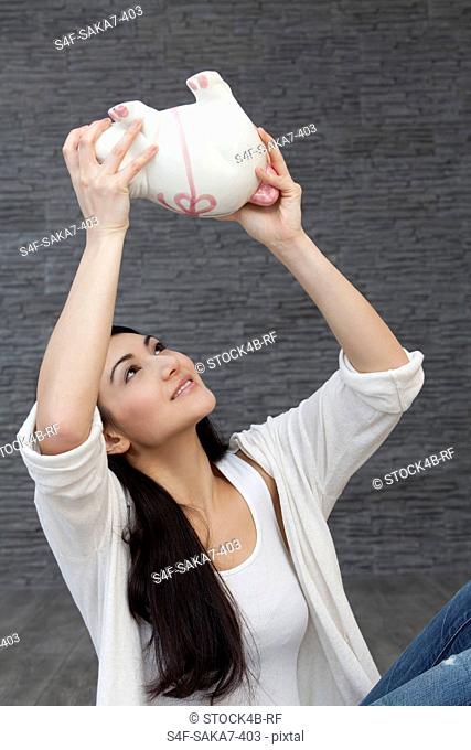 Young woman looking up to piggy bank