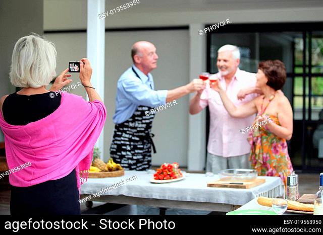 Elderly woman photographing a group of senior citizens in the process of toast