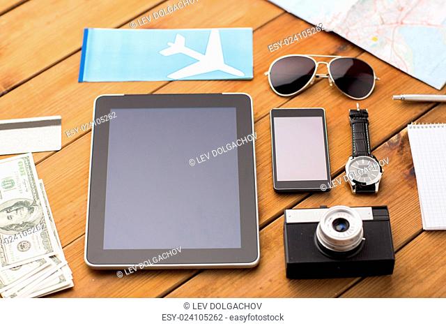 travel, tourism, technology and objects concept - close up of smartphone with tablet pc computer, airplane ticket and personal stuff