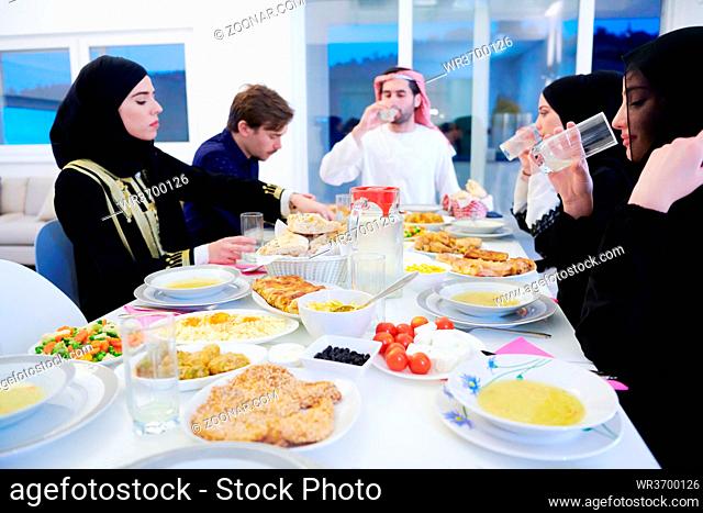 Eid Mubarak Muslim family having Iftar dinner drinking water to break feast. Eating traditional food during Ramadan feasting month at home